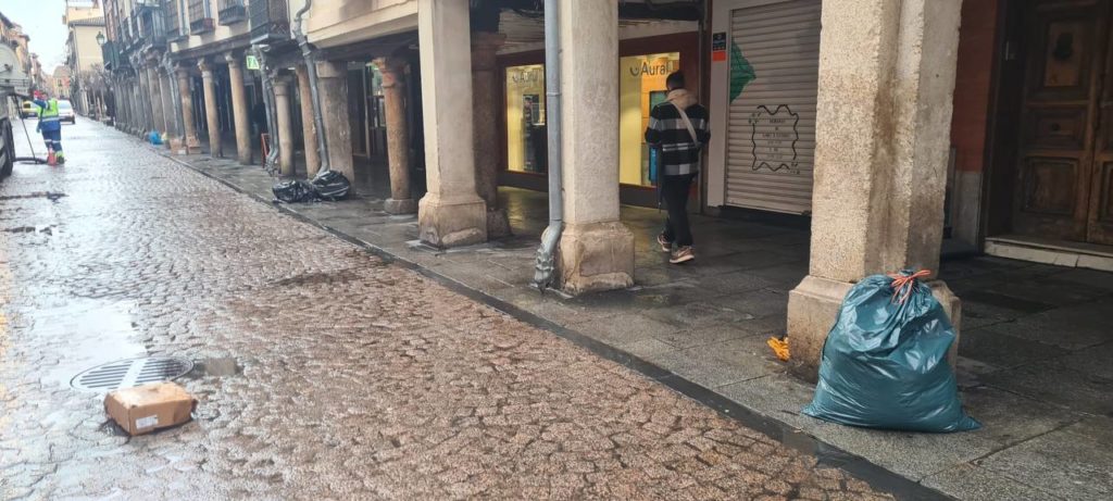 Imagen de la calle Mayor con basura apoyada en las columnas y tirada en el suelo