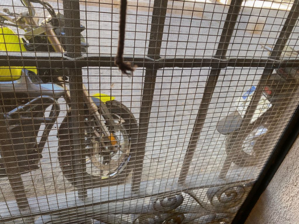 Motocicleta aparcada en la calle frente a la ventana de una vivienda