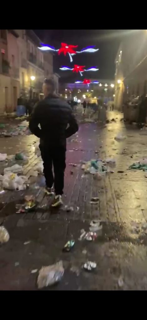 Persona caminando por la calle llena de restos de basura